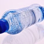 Bottiglia d'acqua su sfondo naturale, simbolo di corretta idratazione e salute.